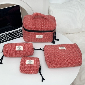 Set di quattro borse da trucco trapuntate rosse con nappe su un tavolo bianco
