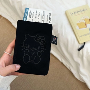 Travel passport holder in black fabric with embroidered cartoon cat design and boarding pass
