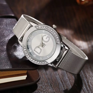 Detail shot of silver mesh strap watch with crystal bezel and DG initials on the dial