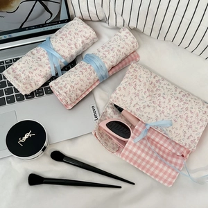 Detail der floralen Make-up-Rolltasche mit Schleifenband und inneren Staufächern