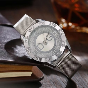 Detail of silver mesh band watch with rhinestone bezel and glitter dial on a wooden table