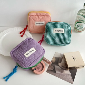 Close-up of three quilted checkered cosmetic bags with colorful zippers and woven labels