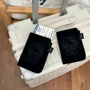 Detail of black velvet passport holder featuring cute cat embroidery on luggage