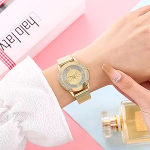 Detail of gold mesh strap watch with sparkling rhinestone bezel and logo dial