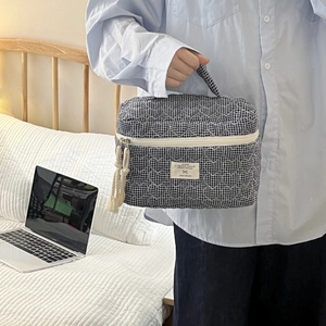 Détail de la trousse de toilette matelassée bleue avec fermeture à pompon et étiquette