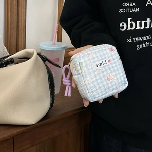 Detail of light blue plaid foam storage bag with pink floral pattern and zip puller