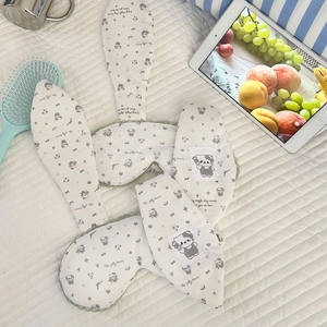 Detail of soft knit bunny ear sleep mask with cute cartoon patch on quilted bedding