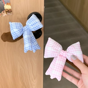 Detail of knitted door handle covers with blue and pink gingham bow and embroidery