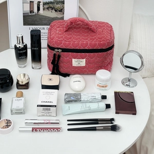 Dettaglio della borsa trucco rossa trapuntata con cuori e vari prodotti di bellezza