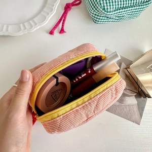 Quilted orange gingham makeup bag with yellow zipper and internal storage compartments