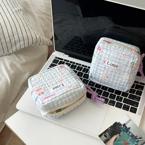Detail of two lime quilted storage bags with bear prints on a white laptop keyboard