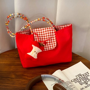 Detail of red checkered tote bag with colorful beaded handle and cute plush apple charm