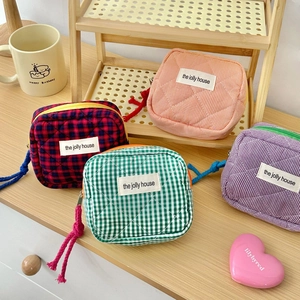 Quilted checkered makeup bags in pastel colors with cotton rope zipper pulls on wood