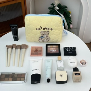 Detail of yellow quilted makeup bag with baby bear embroidery and cosmetics storage