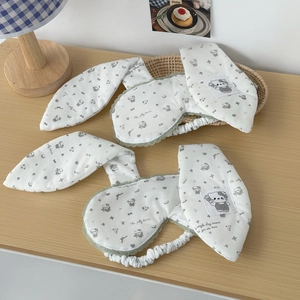 Detail of bunny ear sleep masks with bear prints and green lace trim on a wooden desk