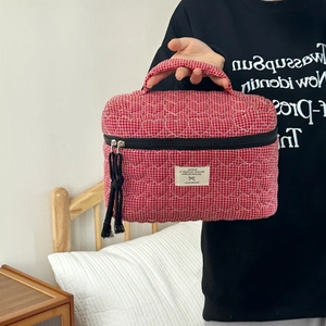 Dettaglio della borsa trucco vichy rossa con cuciture a cuore e lunga nappa nera sulla zip