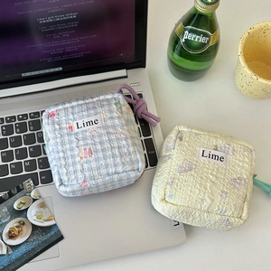 Close-up of quilted cosmetic bags in blue plaid and floral patterns with Lime logo
