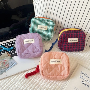 Detail of four quilted plaid makeup bags with textured patterns and zipper pulls