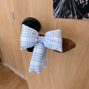 Close-up of blue plaid bow door handle cover with embroidered Weekend Kiss text