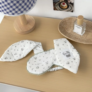 Detail of white cotton sleep mask featuring long rabbit ears and green lace trimming