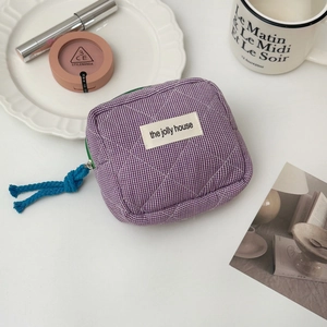 Detailed close-up of purple gingham quilted storage bag with blue pull cord and brand label