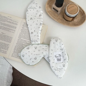 Detail showing the white cotton sleeping mask with bunny ears and lace trim on a tray