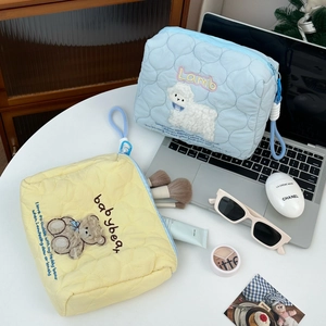 Detailed macro view of quilted cotton cosmetic bags with lamb and bear embroidery