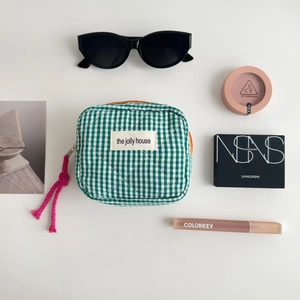 Close-up of green gingham quilted makeup bag with pink tassel and interior compartments