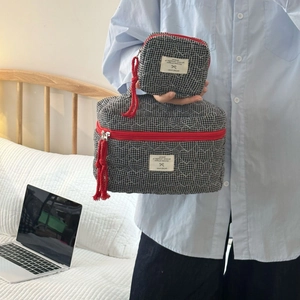 Détail de pochettes matelassées à carreaux noirs et blancs avec zip rouge et pompon