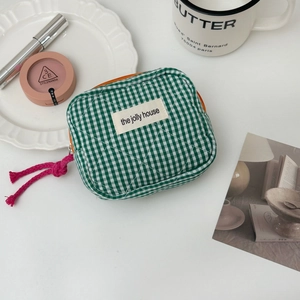 Detail of green gingham makeup bag with orange zipper and pink rope puller