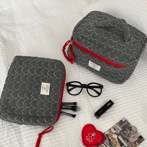 Détail de trousses à carreaux matelassées en cœur avec zips rouges et accessoires