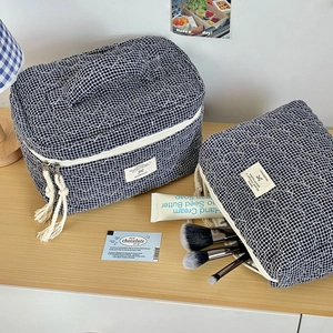 Trousse à maquillage matelassée à carreaux bleus avec glands sur bureau en bois