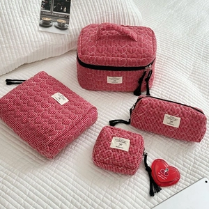 Dettaglio di borse da toilette trapuntate rosse con motivi a cuore e zip con nappe