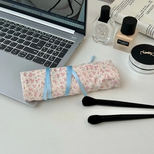 Nahaufnahme der floralen Make-up-Pinseltasche mit Schleifenband auf einem Schminktisch