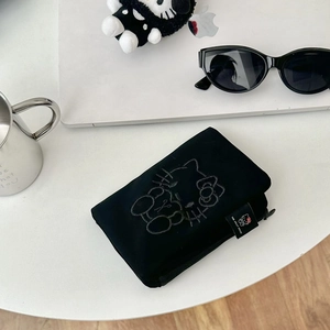 Detail of black fabric passport holder featuring a cat embroidery and secure zipper close