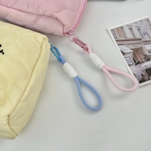Detail of pink and yellow quilted cosmetic bags featuring decorative rope knot zipper pulls