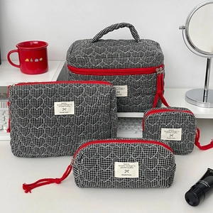 Détail du set de quatre trousses de maquillage matelassées avec fermetures éclair rouges