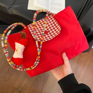 Close-up of red plaid tote bag featuring colorful beaded straps and plush apple charm
