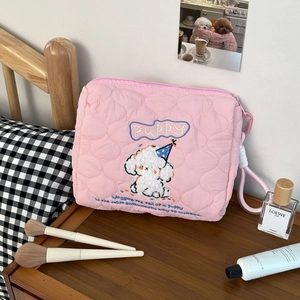 Detailed close-up of pink quilted makeup bag with dog embroidery and zipper lanyard