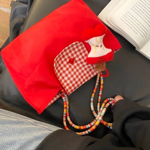 Detail of red tote bag with checkered pocket, colorful beaded strap and apple core charm