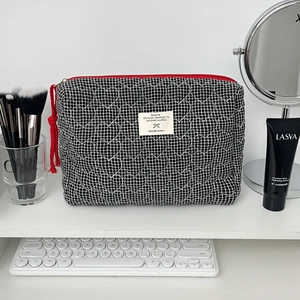 Détail du vanity à damier noir et blanc matelassé en cœur avec fermeture rouge et gland