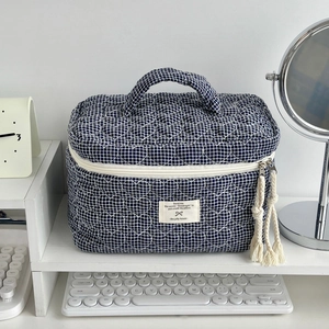 Détail de la trousse à maquillage à carreaux bleus avec matelassage en cœur et pompon