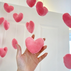 Close-up of soft pink plush heart pendant with detailed texture and white hanging string