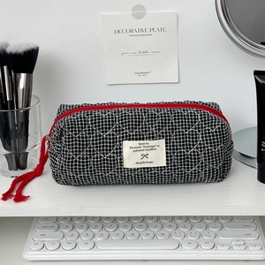 Détail de la trousse de maquillage à carreaux avec cœurs et fermeture à gland rouge