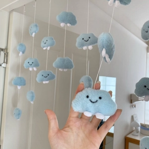 Close-up of light blue plush cloud hanging decor with cute smiling face and soft feet