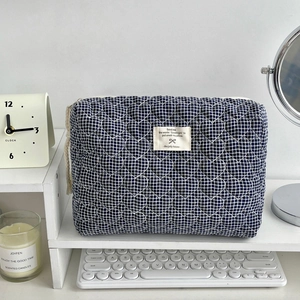 Détail d'une trousse à maquillage à carreaux bleus avec surpiqûres cœurs et étiquette