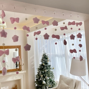 Close-up of pink plush star and bow ornaments on a decorative hanging door curtain