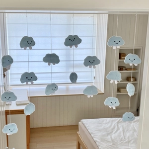 Close-up of light blue plush cloud hanging decor with embroidered smiles for nursery room