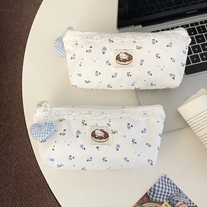 Close-up of floral canvas pencil case with lace trim and heart-shaped blue checkered charm