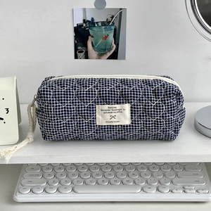 Détail trousse de maquillage bleue matelassée en cœurs avec fermeture et étiquette